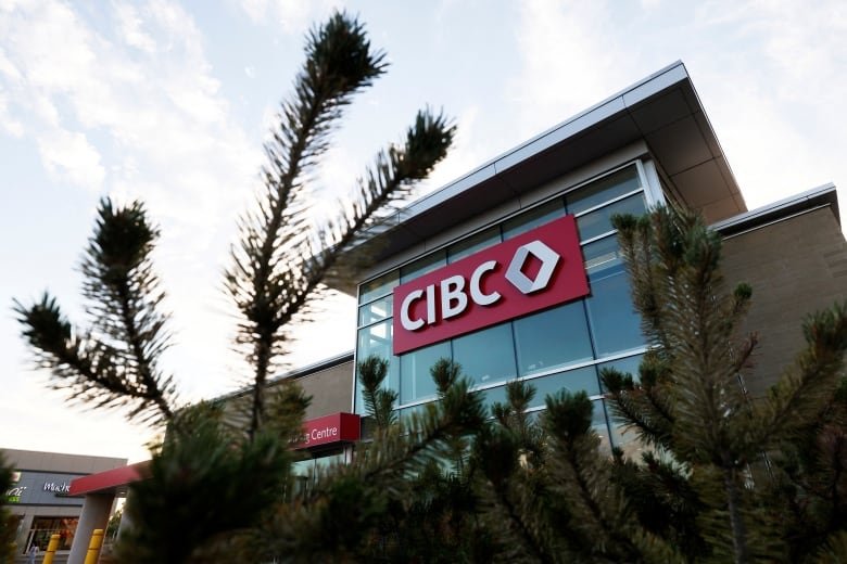 A tree branch waves in front of a stone and glass building with the letters CIBC.