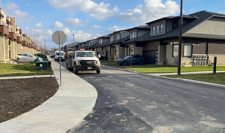 Townhouses with cars in the driveways line a paved street.