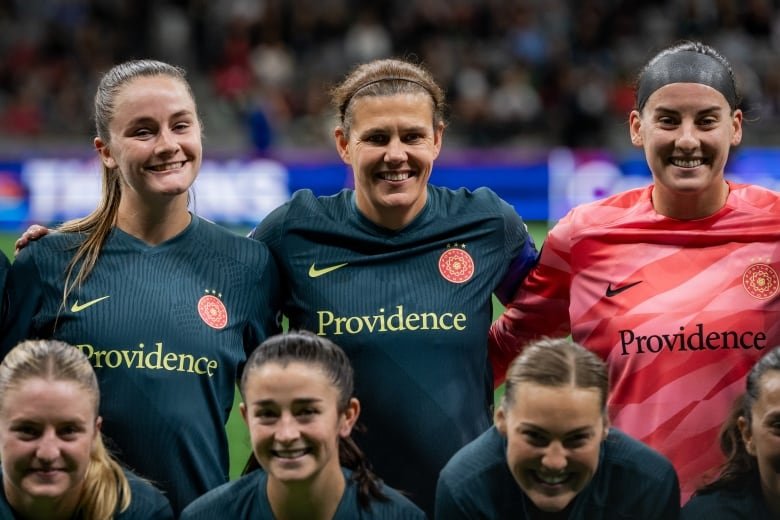 A group of soccer players smile for a picture.