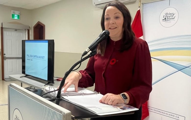 A woman stands behind a podium speaking.