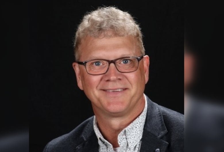 A man with short hair and eyeglasses poses for a portrait