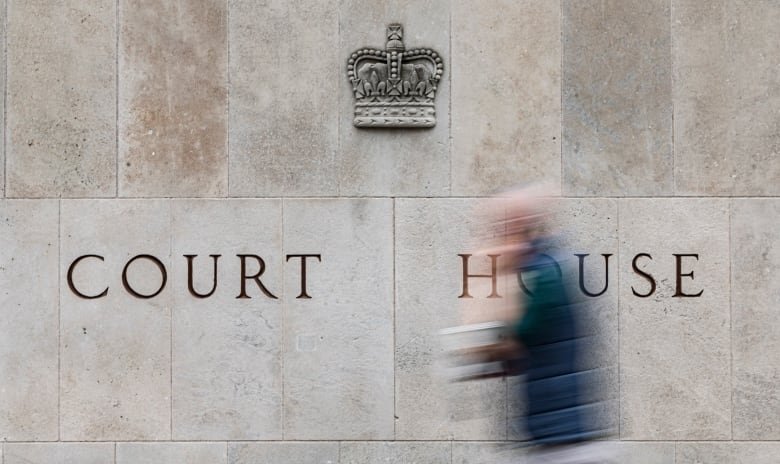 A person walks in front of a courthouse building.