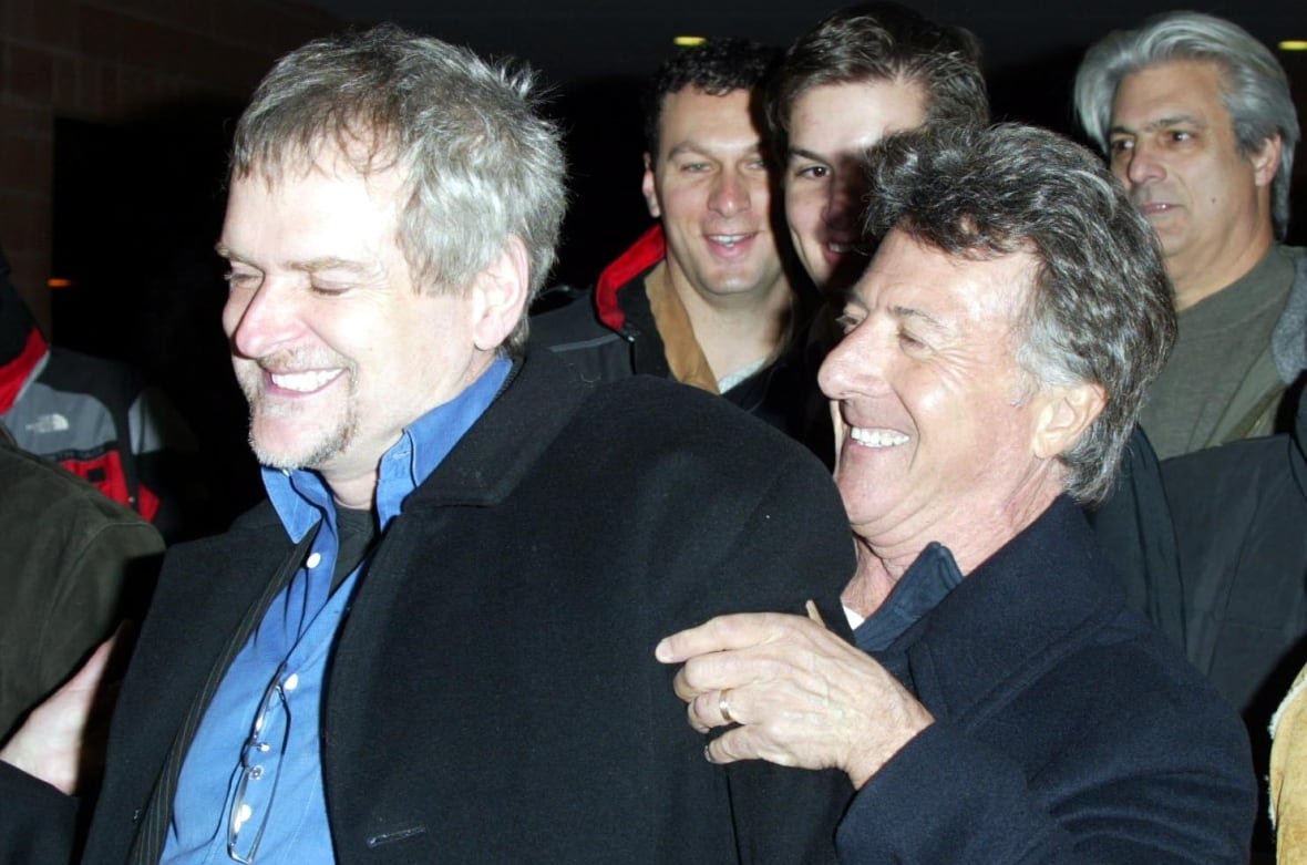 1734730 Two men are seen smiling, with the man on the right standing slightly behind the first man, with his hand on his arm. They appear to be in the middle of walking somewhere, though they are shown from the waist up, and three other men are visible close behind them.
