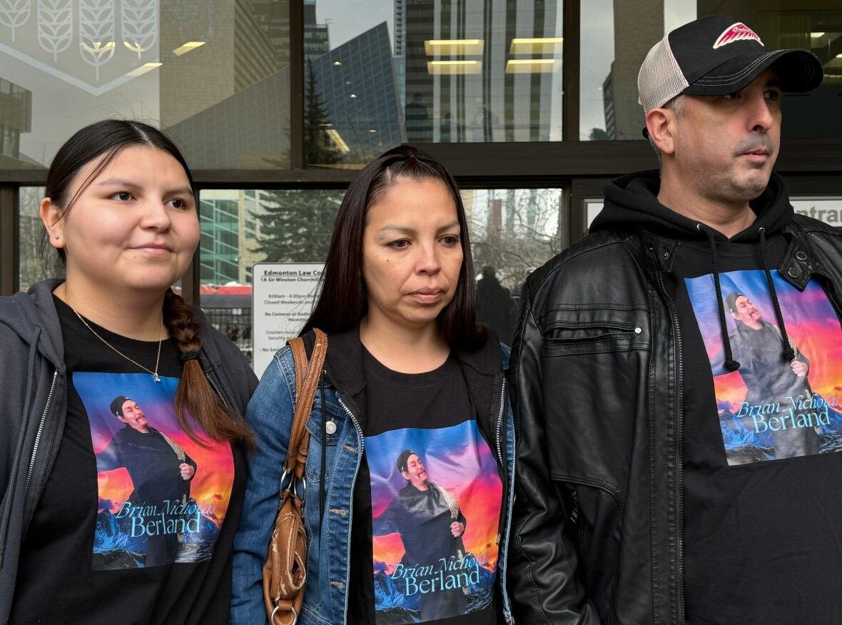 brian-berland-family Three people stand outside wearing a shirt with a picture of a man and the name Brian Nicholas Berland.