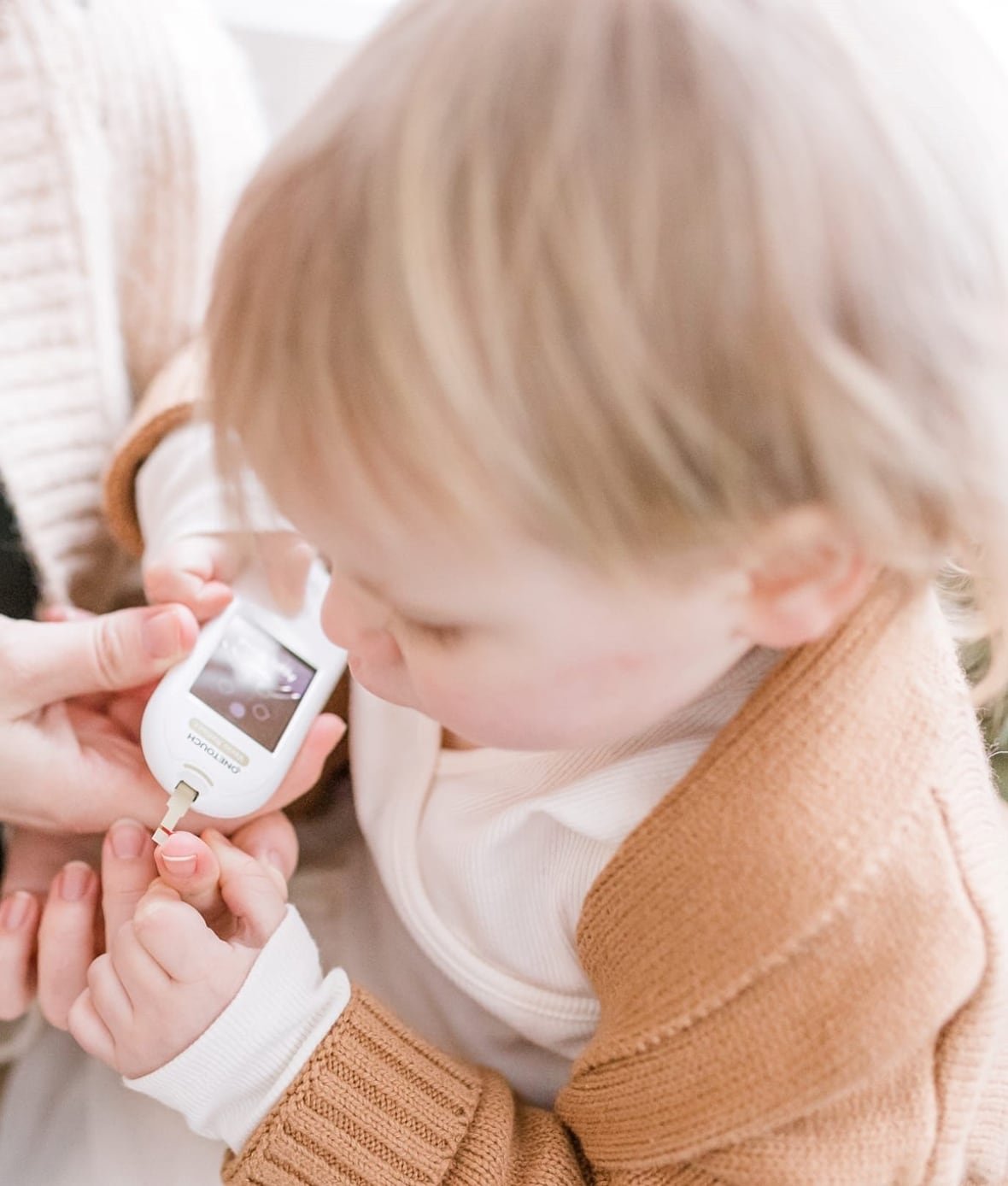 child-uses-glucometer A blond child’s finger is pricked with a medical machine