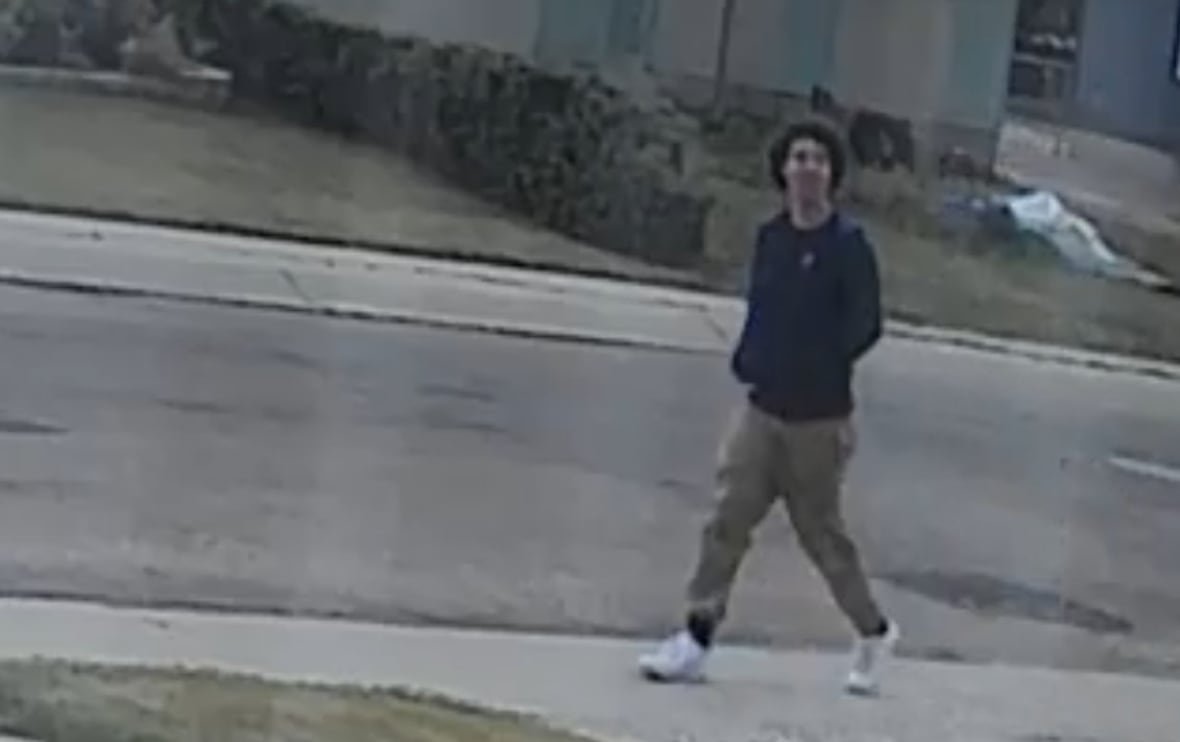 clarence-lawrence-cctv A man wearing a black sweatshirt and green pants is seen walking through a residential neighbourhood in CCTV footage.
