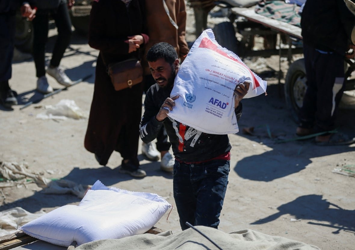 israel-palestinians-gaza-ceasefire A man carries a sack of flour.