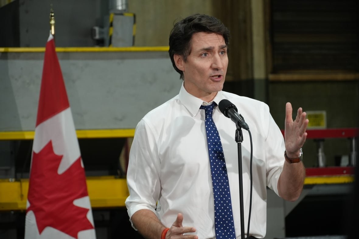 justin-trudeau-1 Trudeau standing at a microphone with a Canadian flag behind him.