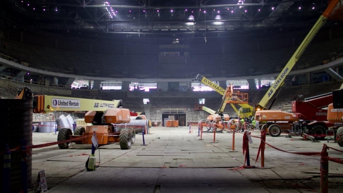 hamilton-arena-redevelopment An arena under construction as seen from ground level. There is dust in the air, and cranes parked where the ice surface would be.