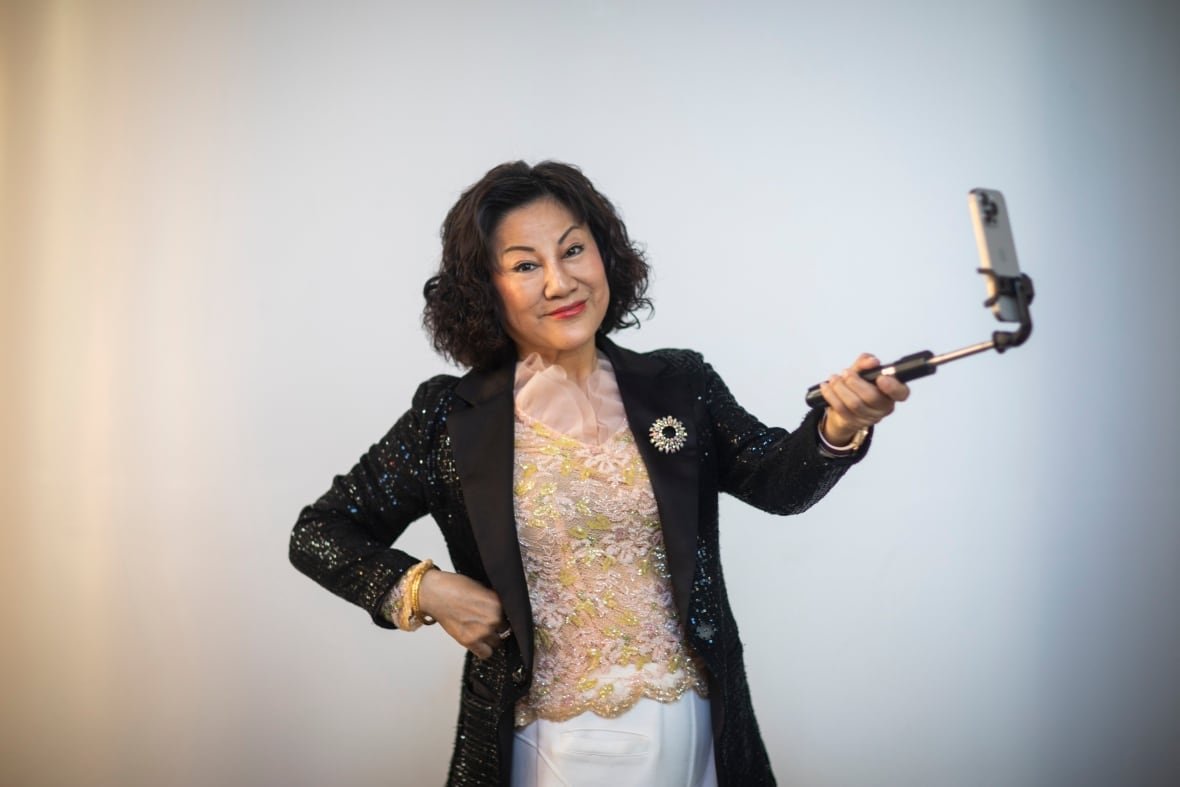 ruby-liu-1 An East Asian woman smiles while holding a selfie stick.