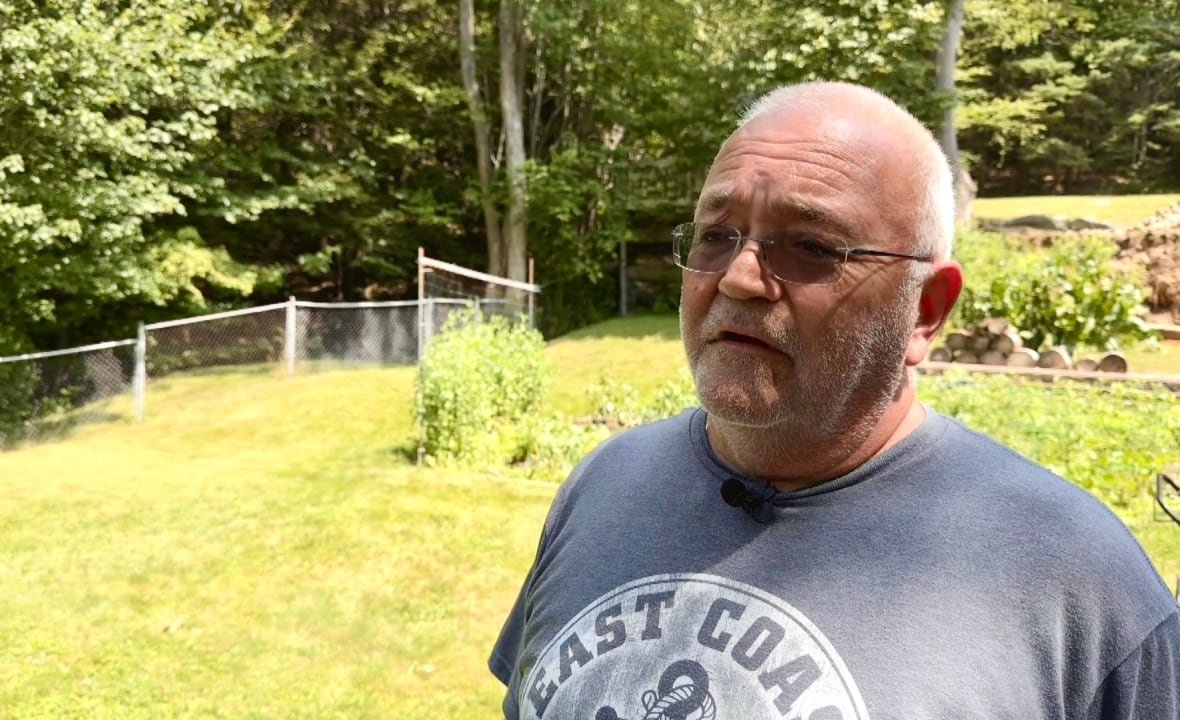 shawn-spurr A man standing in a yard wearing glasses and a t shirt.