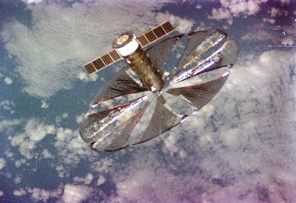 default-882 A grainy image of a satellite with circular, shiny material deployed.