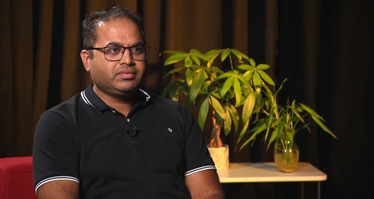 Man sitting in red chair with plants behind him