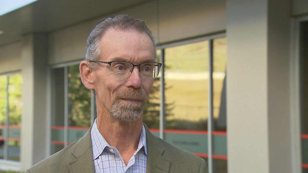 A man stands in front of a building.