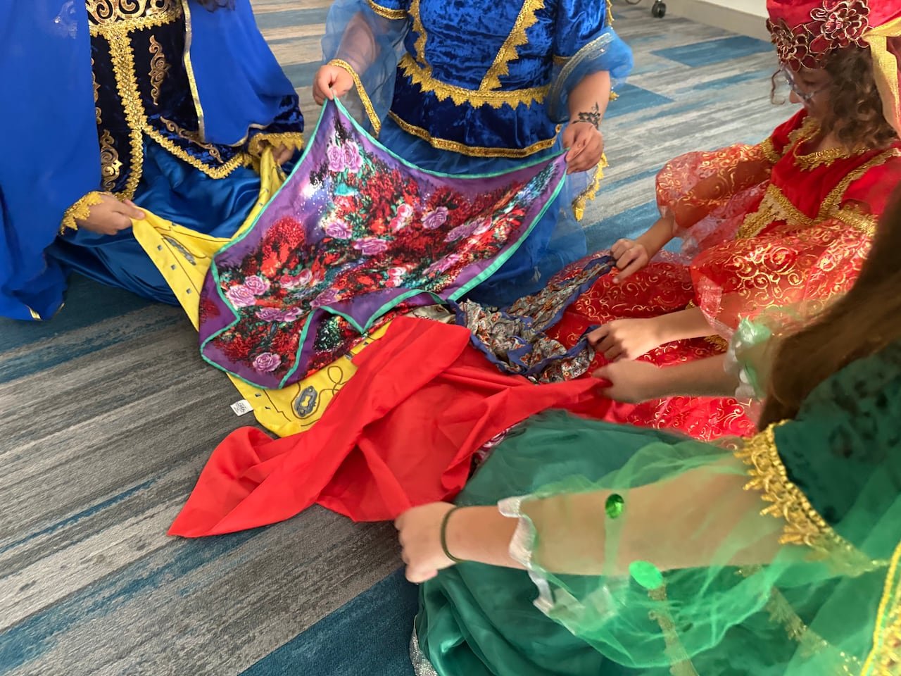 default-466 Hands holding colorful fabric scarves above the ground in a circle.