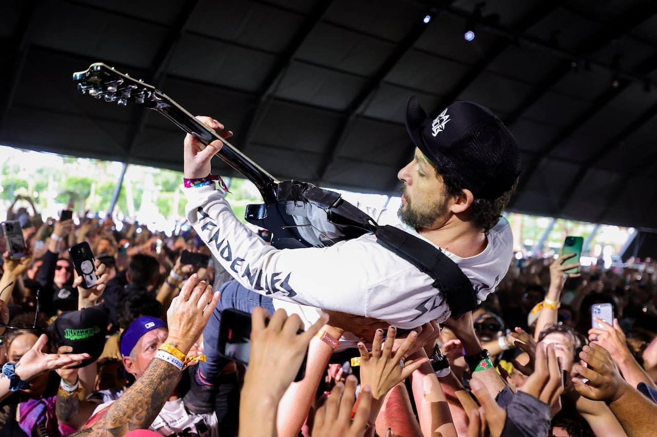A guitarist crowd-surfing and playing his instrument during a live show.
