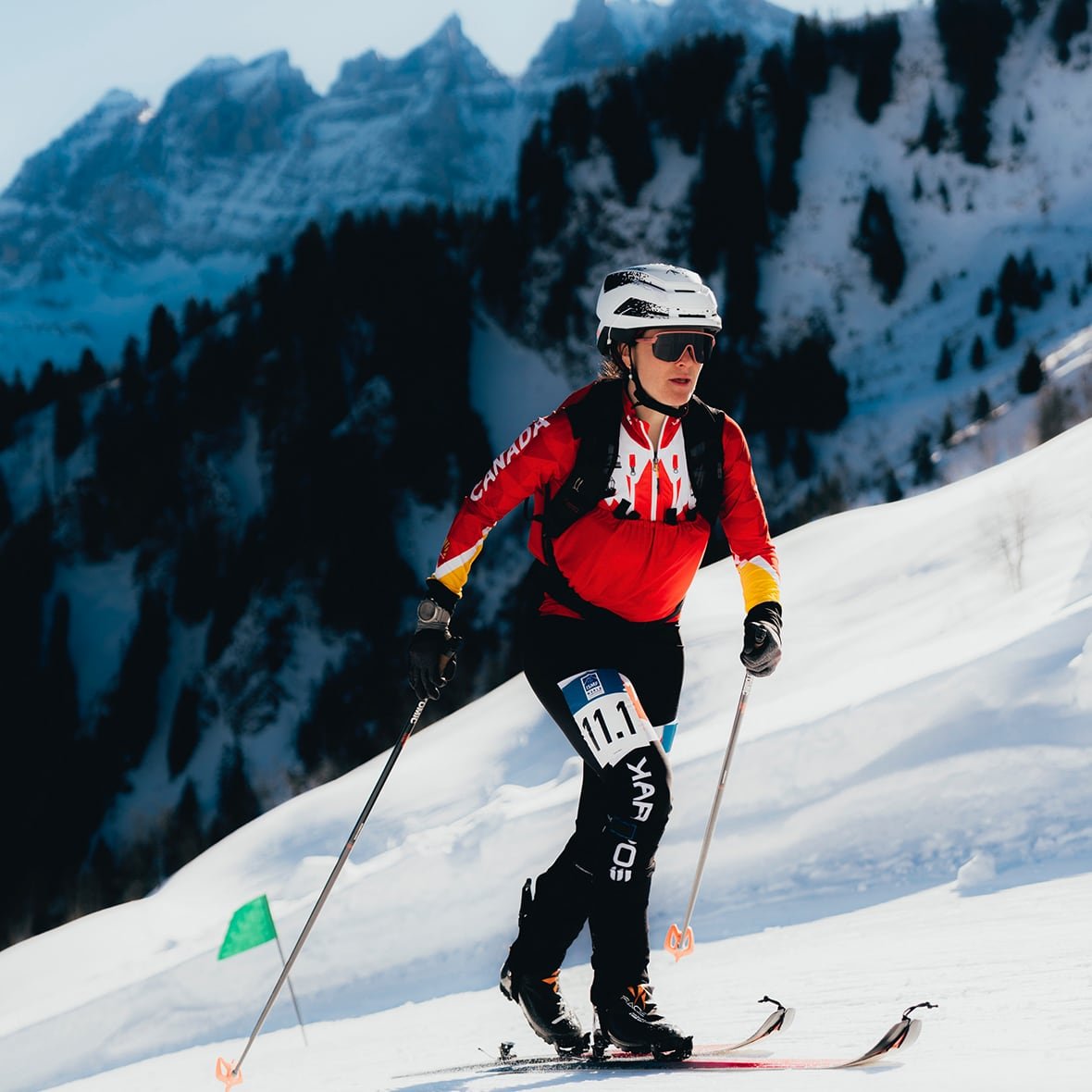 default-65 A women's skier climbs a ski hill with a mountain range in the background.