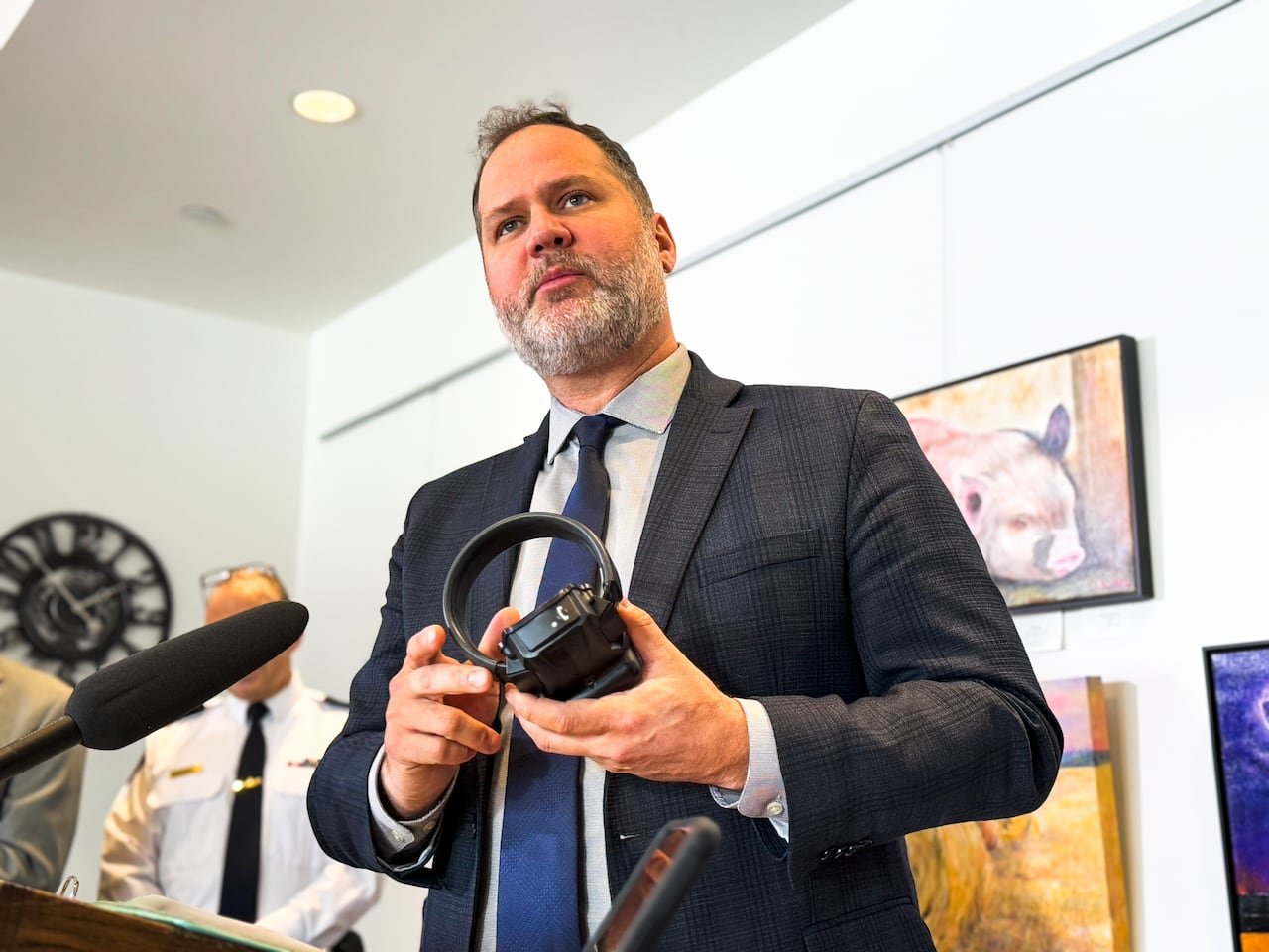 A man in a suit and tie holds a device.