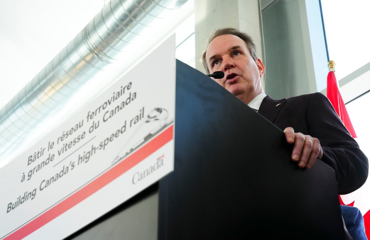 A man in a suit speaks at a podium.